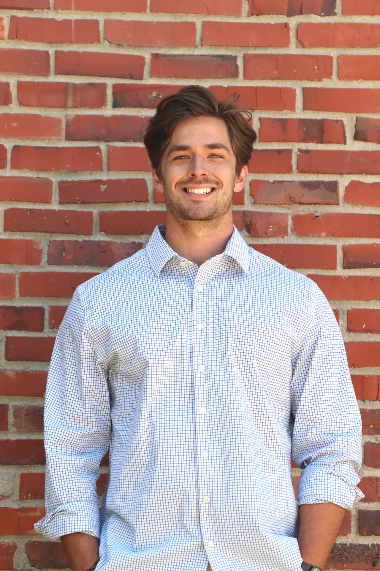 Danny Fisher smiling in front of a brick wall