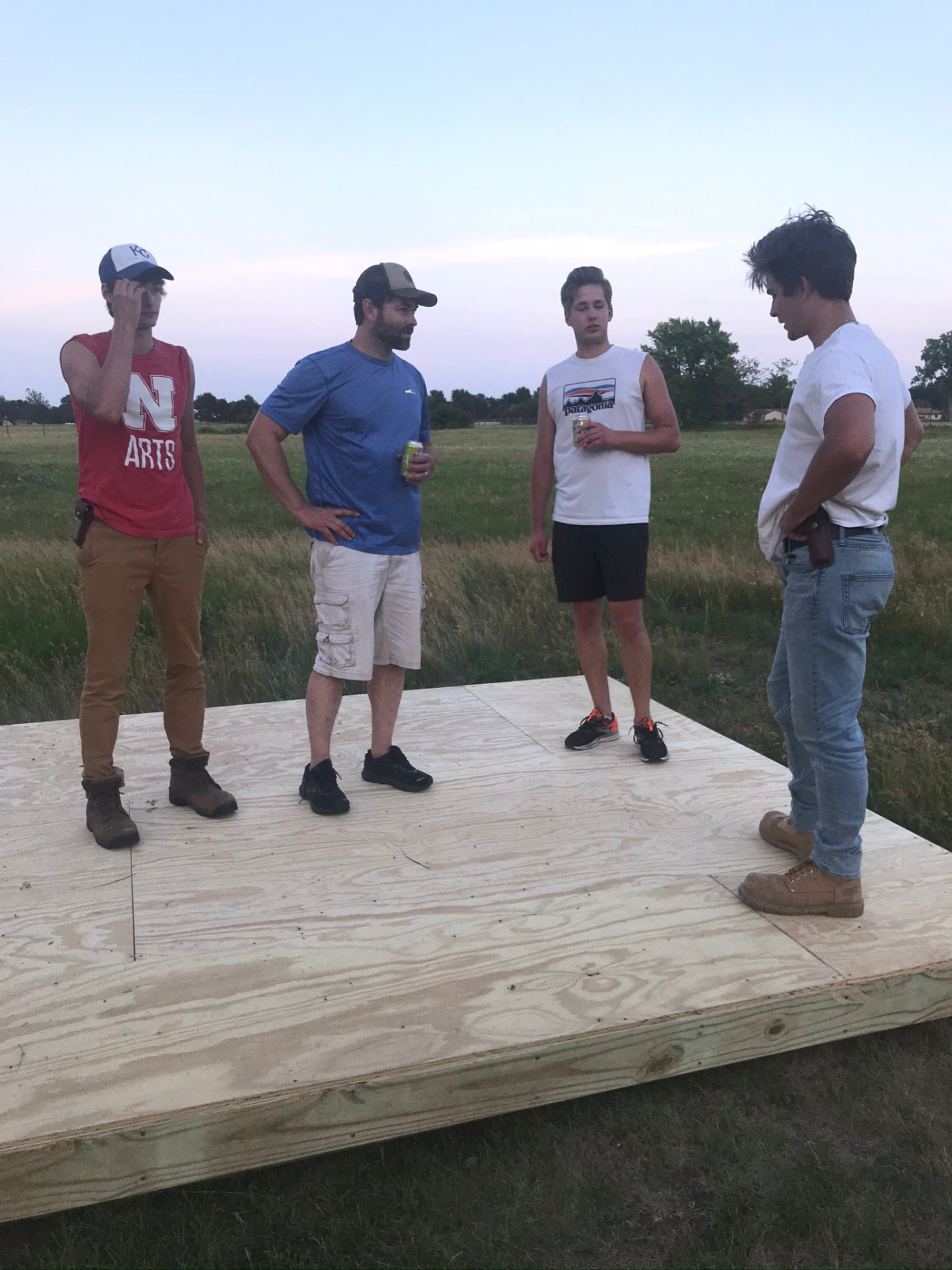 Danny, his father, and brothers standing on the finished floor of the shed at dusk