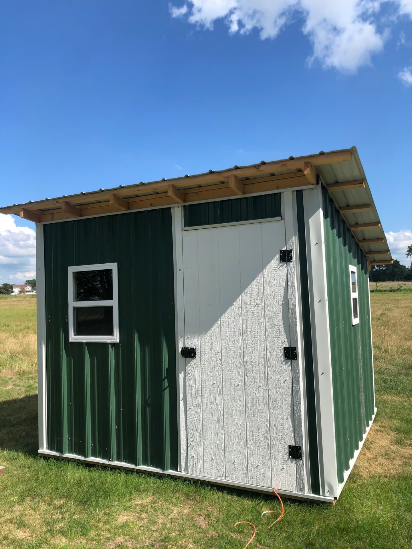 The finished green-sided God cave shed with a white door